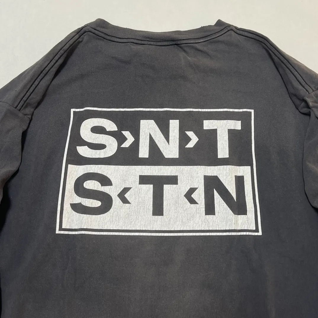SAINT Mxxxxxx S>N>T LS TEE/BLACK Autumn and winter new style S>N>T slogan crack printed long TEE, washed black S-XL Asut ready-made garments dyed, the whole piece sprayed with horse-hair spray, and then sprayed again to fade the color. The collar and cuffs are frayed. Many hangings are worn NEW VINTAGE. Heavy craftsmanship.